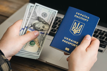 Ukrainian biometric passport and dollar bills in the hands of a man.の写真素材