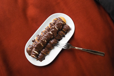 Mini pancakes with banana, poured with chocolate in a plate in bed, top view.の写真素材