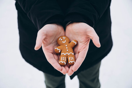 Gingerbread man in the hands of a man against a background of snow, close-up.