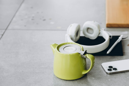 Green teapot, headphones, smartphone and notepad on a blurred background.の写真素材