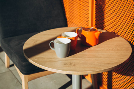 Two cups and a teapot on a table in a cafe with hard shadows.の写真素材