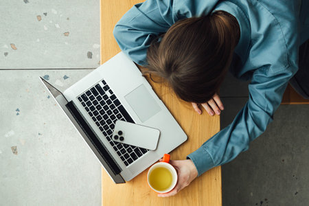 Tired female student sleeping at table with laptop, top view.の写真素材
