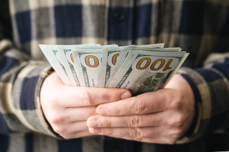 Close up, one hundred dollar bills in male hands, finance and budget.の写真素材