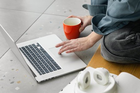 Close-up of hands, female student using laptop and drinking coffee.の写真素材