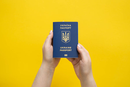 Passport of a citizen of Ukraine in a female hand on a yellow background.の写真素材