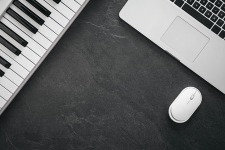 Musician work set with synthesizer, laptop and computer mouse on a textured black background. Concept of writing music, creates a song, flat lay, top view, space for text.の写真素材