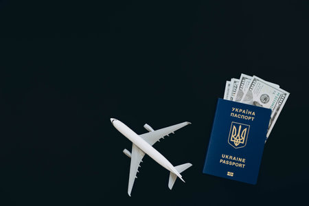 Ukrainian passport, money and airplane on a black background, top view.の写真素材