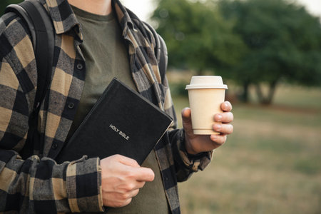 Bible and paper cup in the hands of a Christian man outside.