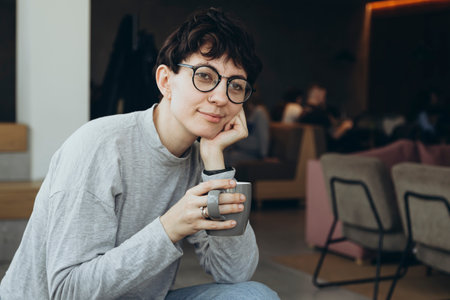 Sleepy young woman with a cup of coffee in the morning in the office.