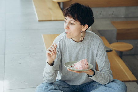Stylish woman enjoying a piece of cake in a modern cafe.