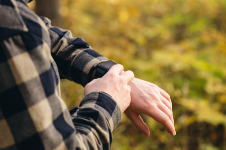 Close up, man using smart watch, setting up his smart watch in the forest.の写真素材