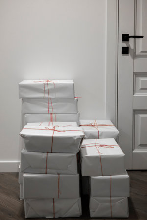 A pile of Christmas gifts in white wrapping against the wall on a floor.の写真素材