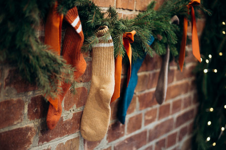 Christmas socks with bows and Christmas tree branches hanging on brick wall.の写真素材