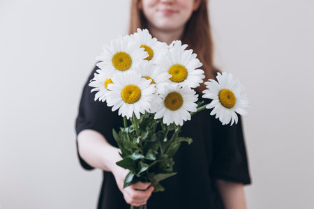 Beautiful young woman with chamomile flowers on light background.の写真素材