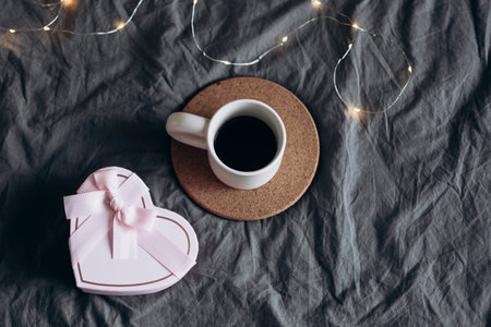 A cup of coffee and a heart-shaped gift on the bed, Valentines Day concept.の写真素材