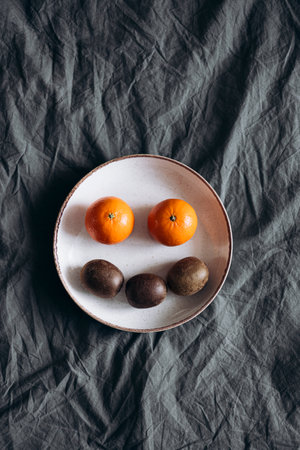 Fresh kiwi and orange fruits in a plate on the bed, top view.の写真素材