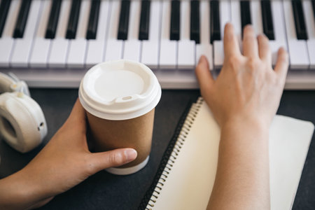 A cup of coffee in the hands of a female keyboard player at the workplace.の写真素材