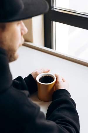 Man with hands clasped near yellow mug of filter coffee on bright tabletop.の写真素材