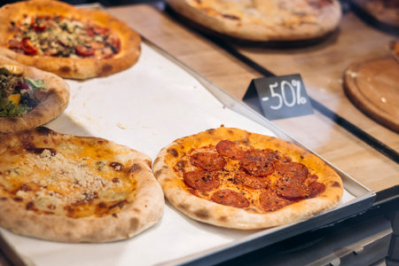 Pizzas displayed for sale in a shop window, close-up of delicious fast food.の写真素材
