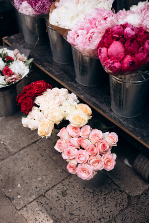 Roses and peonies in buckets at outdoor flower market in natural daylight.の写真素材