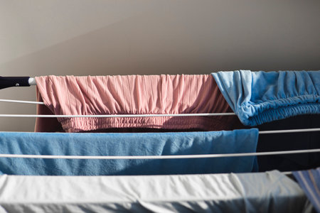 Clear blue and pink clothes hanging on dryer, close up.