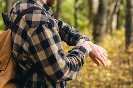 Close up, man using smart watch, setting up his smart watch in the forest.の写真素材