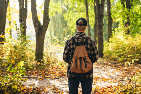 Traveler with a backpack is walking on an road along autumn forest.の写真素材