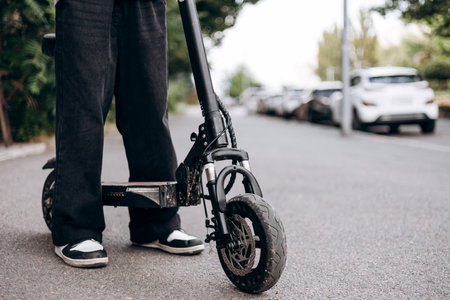 Close-up of an electric scooter wheel with a teenage boy riding on a street.の写真素材