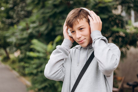 Teen boy listening to music with headphones outdoors smiling.の写真素材