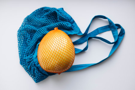 Pomelo in mesh bag on white background, eco shopping concept.の写真素材