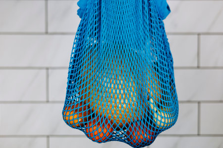 Fruits in blue mesh bag on kitchen counter, healthy lifestyle concept.の写真素材