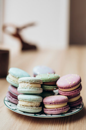 Pastel colored macaroons on a plate on a wooden table, close-up.の写真素材