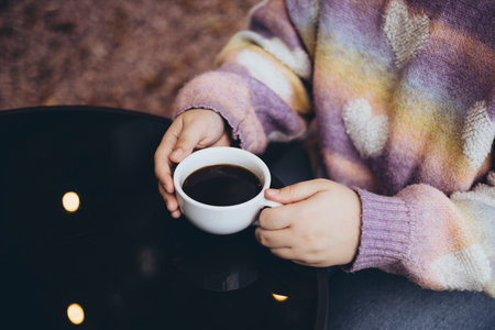 Woman drinking black filter coffee in cafe on terrace in autumn, close up.の写真素材