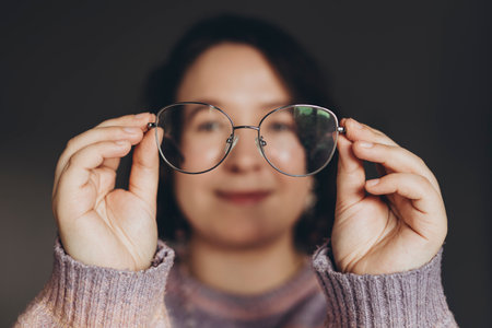 Happy young woman holding eyeglasses in hands, close up.の写真素材