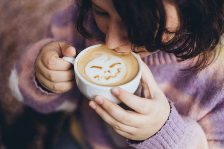 Woman drinks cappuccino coffee with a picture of pumpkin made of milk foam.の写真素材