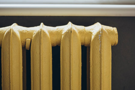 Yellow painted old cast-iron battery at home, close up, heating of the house.の写真素材