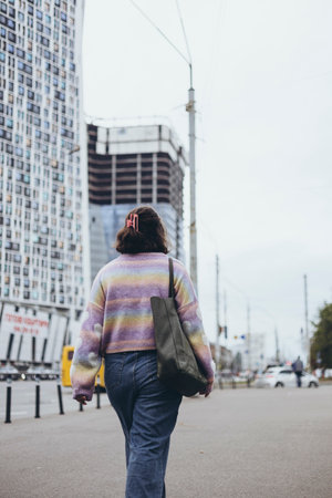A woman with a bag walks down the street in a big city, rear view.の写真素材