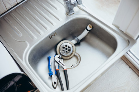 A sink undergoing renovation with the faucet and tools disassembled.の写真素材