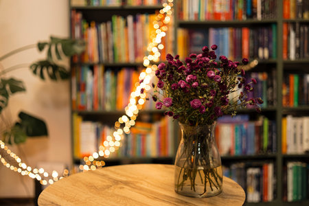 Vase with chrysanthemums on blurred bookstore shelves with space for text.の写真素材