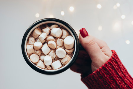 Woman holds Christmas cup of cocoa with with lights bokeh on a white background.の写真素材