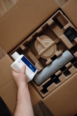 Cleaning solution bottle next to a newly unpacked vacuum cleaner, accessories.