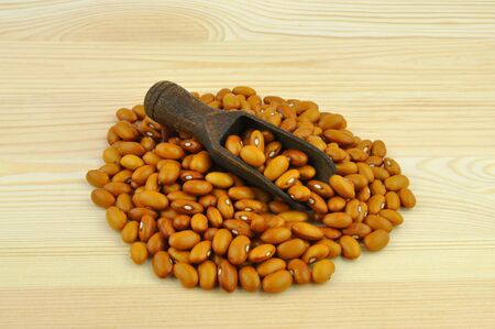 Yellow beans on wooden background with dark spoon