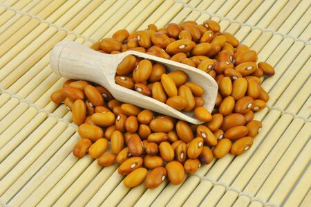 Orange beans on bamboo mat with wooden scoopの写真素材