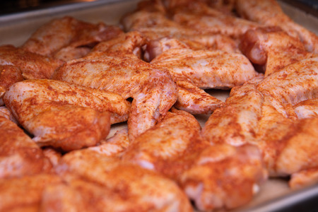 Chicken wings. Raw poultry meat with spices on a baking sheetの写真素材