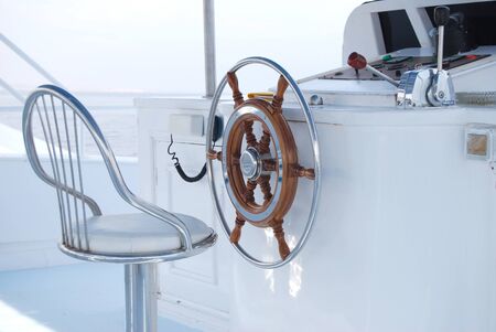 Steering wheel and metal seat on a yacht.