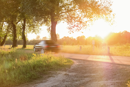 car is driving along a narrow rural roadの写真素材