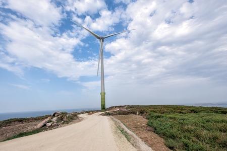 Aerial drone shot of huge electricity windmills in the green field near the seaの写真素材