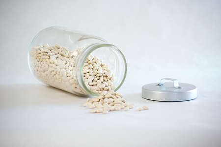 Beans spilling out of a glass jar.の写真素材