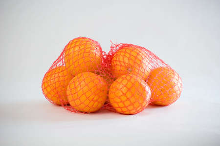 Some fresh oranges in a red net.
