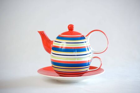 A teapot with stripes on a matching cup and saucer.の写真素材